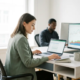 Junger Berufstätiger analysiert Finanzdaten auf Laptop mit Diagrammen auf zweitem Monitor in modernem, hellen Büro.