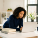 Junge Frau studiert konzentriert am modernen Schreibtisch mit Laptop und Büchern im hellen Büro.