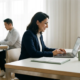 Steuerberaterin mittleren Alters analysiert Finanzdaten auf Laptop, Kollege arbeitet im Hintergrund, modernes Büro mit natürlichem Licht.